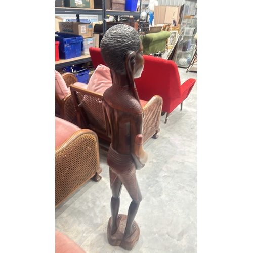 245 - Hand-carved wooden sculpture depicts a traditional African figure with intricate detail, standing on... 