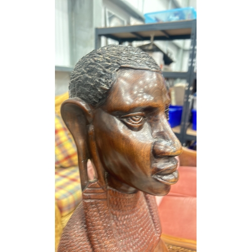 245 - Hand-carved wooden sculpture depicts a traditional African figure with intricate detail, standing on... 