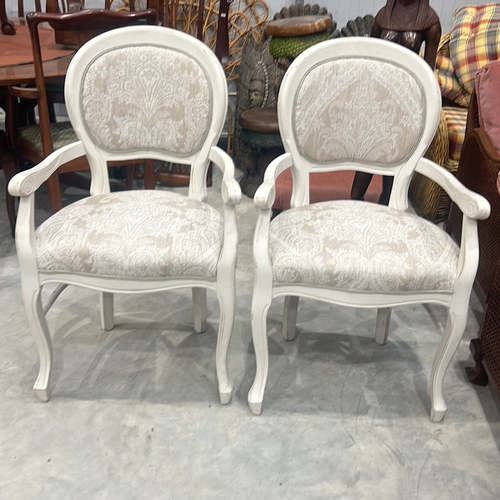 75 - Pair of white wooden armchairs with intricate scroll detailing and paisley-patterned upholstery.