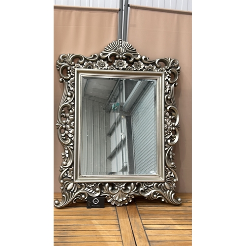 158 - Ornate silver-toned wall mirror with intricate floral design. Rectangular shape. Dimensions approxim... 