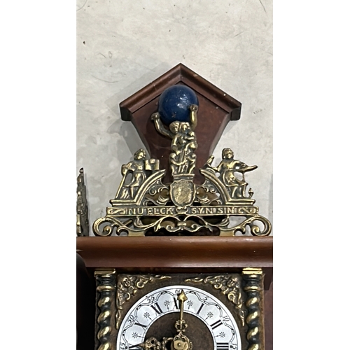 276 - Ornate Vintage Dutch wall clock featuring brass and wood detailing, figurative scene, and Roman nume... 