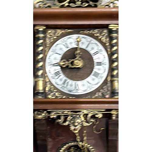 276 - Ornate Vintage Dutch wall clock featuring brass and wood detailing, figurative scene, and Roman nume... 