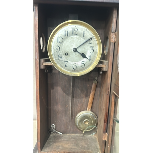 277 - Antique wooden wall clock with carved floral motif, showcasing detailed internal gears.