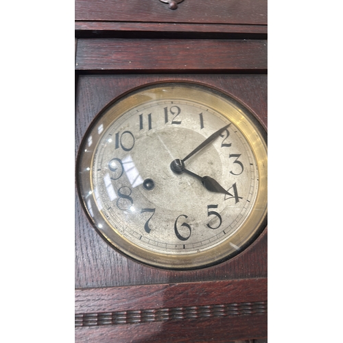 277 - Antique wooden wall clock with carved floral motif, showcasing detailed internal gears.