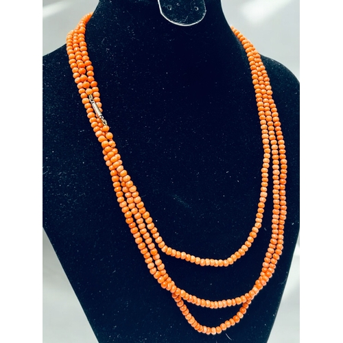 50 - A long 9ct gold clasp coral necklace together with a large polished orange calcite bead necklace.