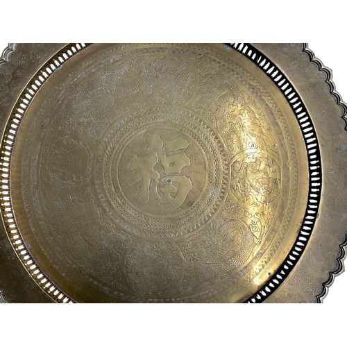 45 - A large Chinese brass top folding Benares table.The scalloped brass tray engraved with entwined Drag... 