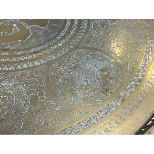 45 - A large Chinese brass top folding Benares table.The scalloped brass tray engraved with entwined Drag... 