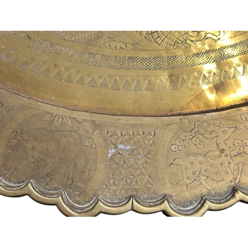 45 - A large Chinese brass top folding Benares table.The scalloped brass tray engraved with entwined Drag... 