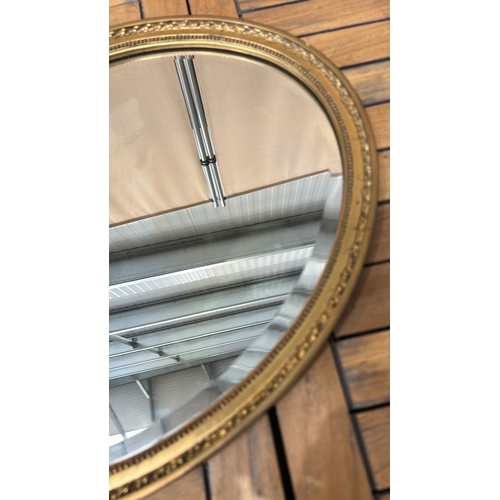 43 - Oval gilt-framed mirror with ornate beaded edge detailing. Sturdy metal hanging fixture on back.