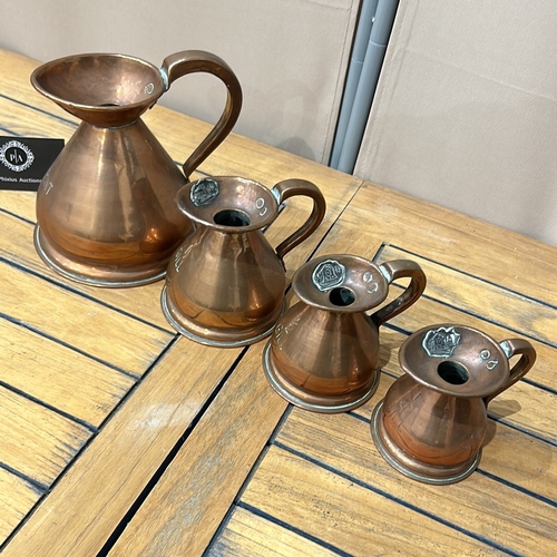 53 - Set of four graduated copper measuring jugs with handles, marked for pint, gill, half gill, and quar... 