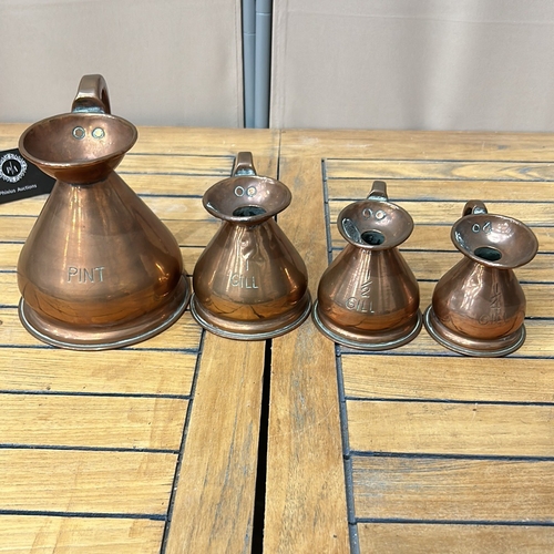 53 - Set of four graduated copper measuring jugs with handles, marked for pint, gill, half gill, and quar... 