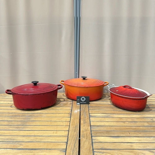 57 - Le Creuset cast iron Dutch ovens, two pieces, enameled in red and orange. Renowned for heat retentio... 