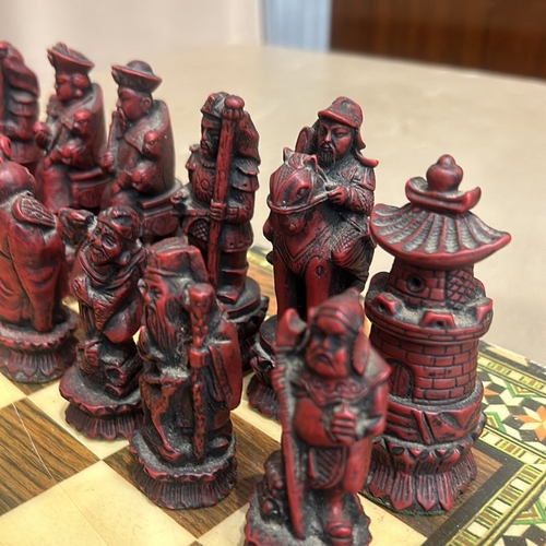 62 - Intricately carved Chinese chess set with detailed figurine pieces on a decorative inlaid board, fea... 