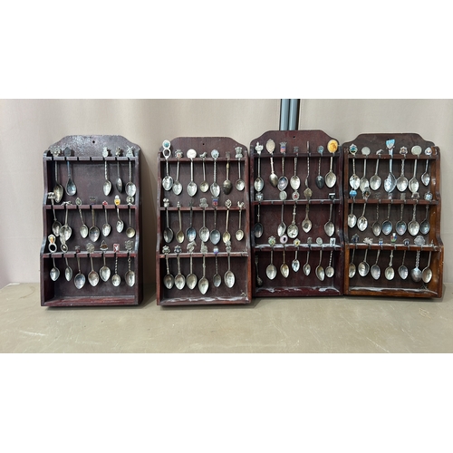 109 - A collection of vintage souvenir spoons with intricate decorative finials, housed in four wooden dis... 