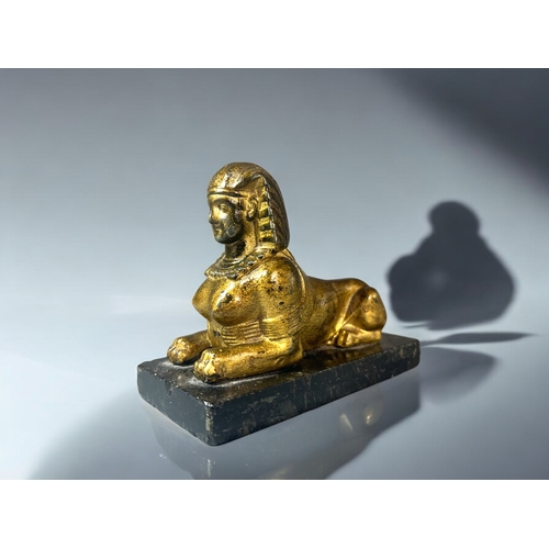 615 - A gilt metal figure of a Sphinx.Mounted on black marble base. 15 x 12cm