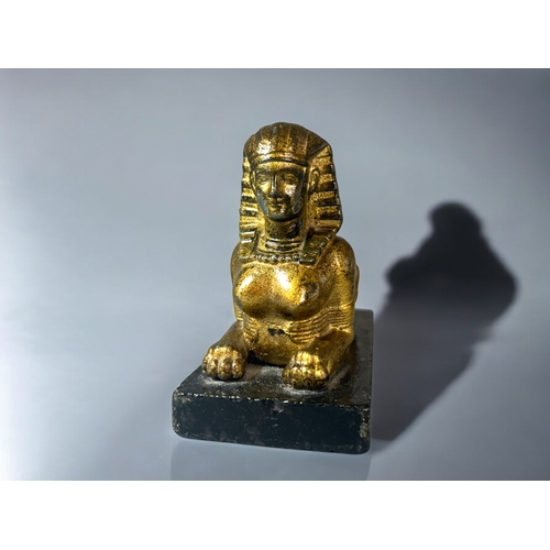 615 - A gilt metal figure of a Sphinx.Mounted on black marble base. 15 x 12cm