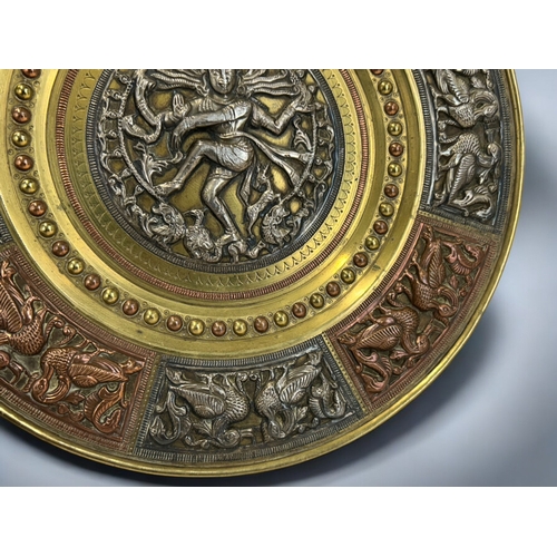604 - An Indian mixed metal tray.Relief decorated central silver roundel depicting Shiva. Bordered with si... 