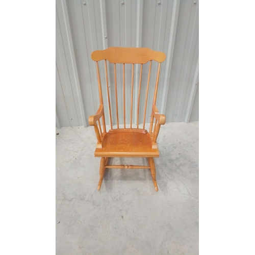 43 - Solid wood rocking chair with spindle back and curved arms, featuring a warm honey-toned finish.