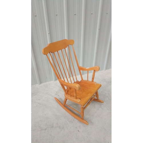 43 - Solid wood rocking chair with spindle back and curved arms, featuring a warm honey-toned finish.