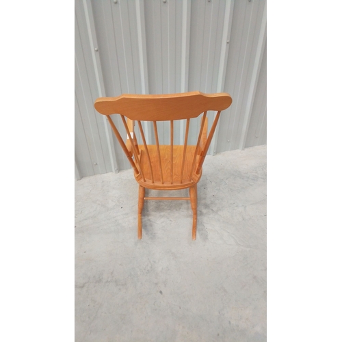 43 - Solid wood rocking chair with spindle back and curved arms, featuring a warm honey-toned finish.