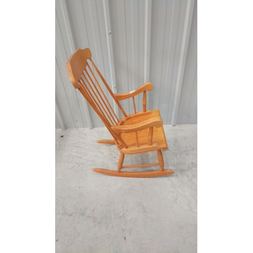 43 - Solid wood rocking chair with spindle back and curved arms, featuring a warm honey-toned finish.