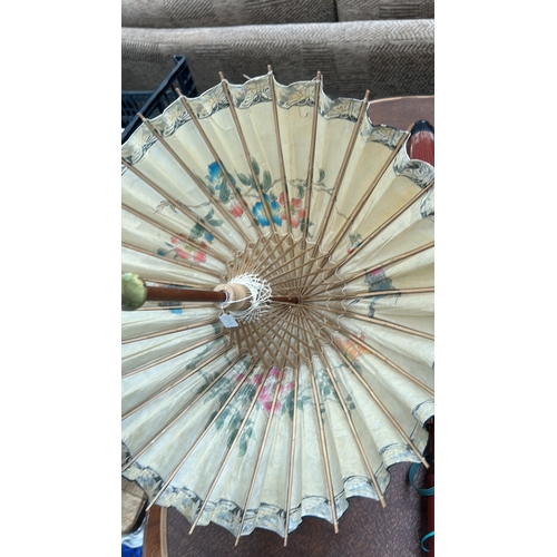 55 - Pair of bamboo-ribbed oiled-paper parasols; one cream ground with polychrome floral sprays, the othe... 