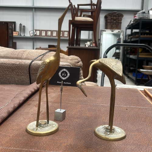 60 - Pair of cast brass crane statuettes, one standing erect, the other bending to feed, each on a textur... 