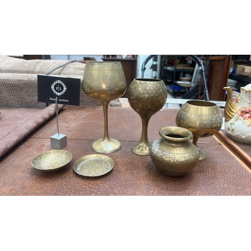 62 - Group of six Indian engraved brass wares: three stemmed goblets, a squat pot and two circular dishes... 