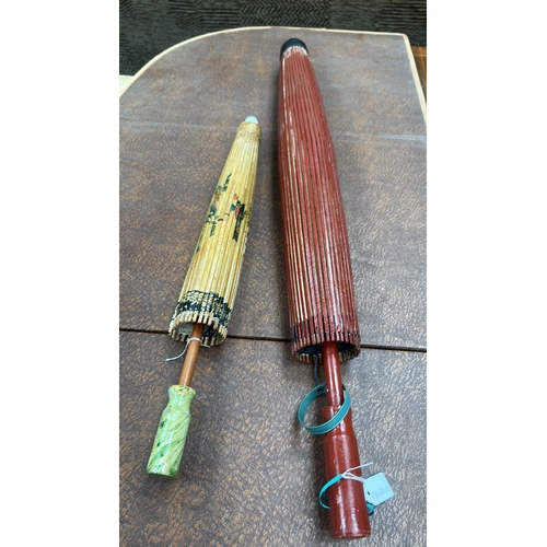 55 - Pair of bamboo-ribbed oiled-paper parasols; one cream ground with polychrome floral sprays, the othe... 