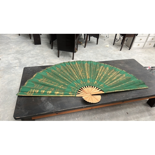 56 - Oversized folding wall fan of bamboo ribs and green fabric leaf, gilt-printed with stylised Thai tem... 