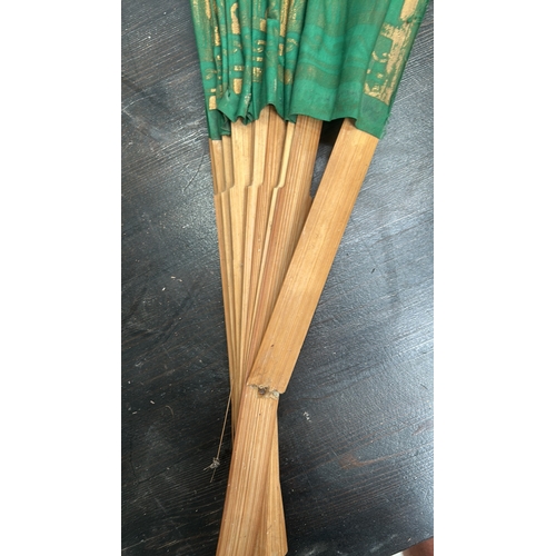 56 - Oversized folding wall fan of bamboo ribs and green fabric leaf, gilt-printed with stylised Thai tem... 