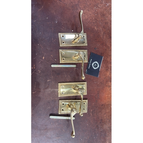 106 - Set of four polished brass lever door handles, each on rectangular rope-twist moulded backplate with... 