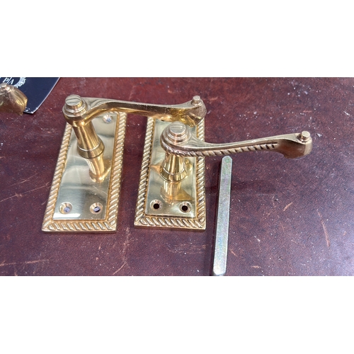 106 - Set of four polished brass lever door handles, each on rectangular rope-twist moulded backplate with... 