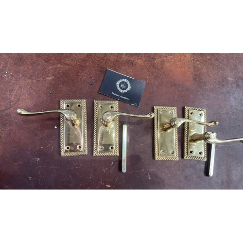 106 - Set of four polished brass lever door handles, each on rectangular rope-twist moulded backplate with... 
