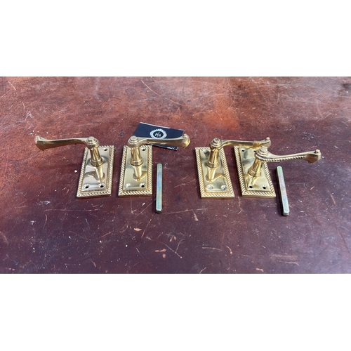 106 - Set of four polished brass lever door handles, each on rectangular rope-twist moulded backplate with... 