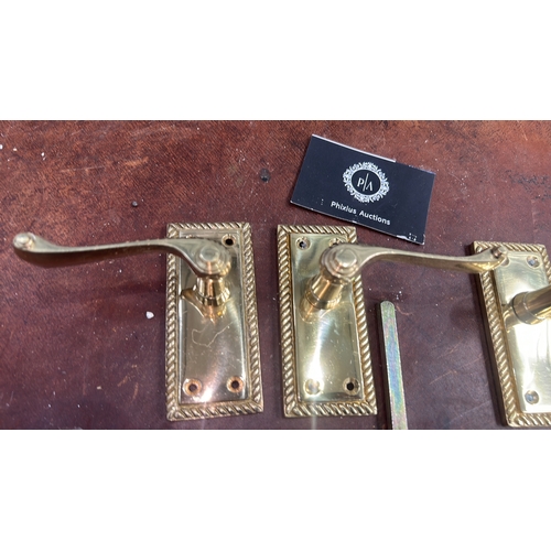 106 - Set of four polished brass lever door handles, each on rectangular rope-twist moulded backplate with... 