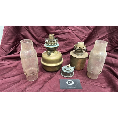 142 - Group of two brass kerosene oil lamps with pierced burners and clear glass chimneys, accompanied by ... 