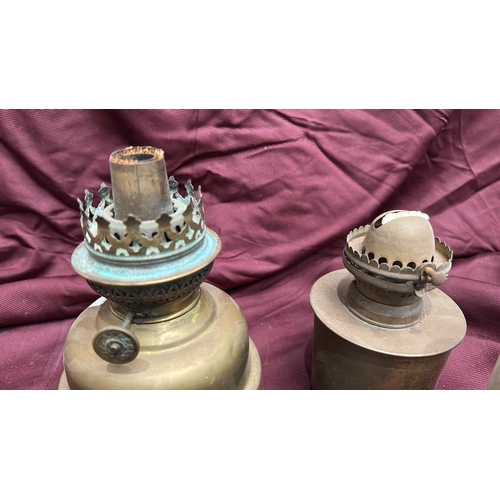 142 - Group of two brass kerosene oil lamps with pierced burners and clear glass chimneys, accompanied by ... 