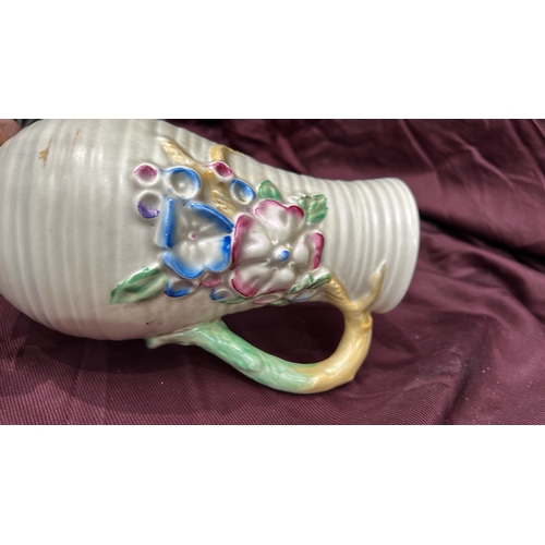 255 - Newport Pottery. Cream-glazed earthenware jug, ribbed body with polychrome moulded floral panels, br... 