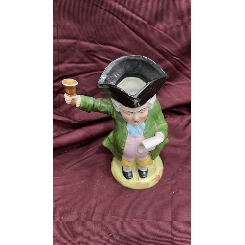 256 - Porcelain character toby jug modelled as a Town Crier with raised bell, tricorn hat forming rim, int... 