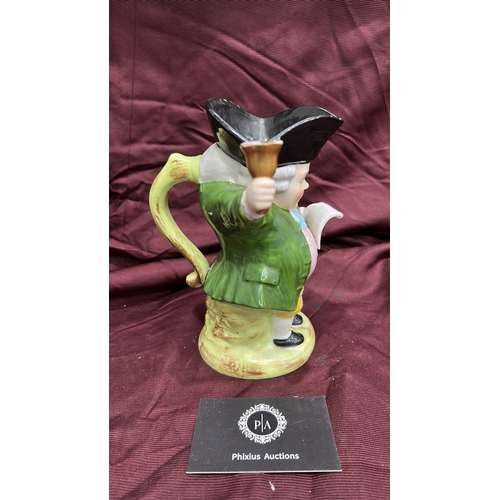 256 - Porcelain character toby jug modelled as a Town Crier with raised bell, tricorn hat forming rim, int... 