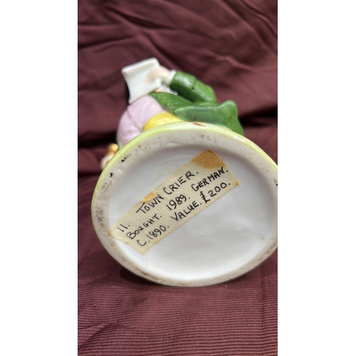 256 - Porcelain character toby jug modelled as a Town Crier with raised bell, tricorn hat forming rim, int... 