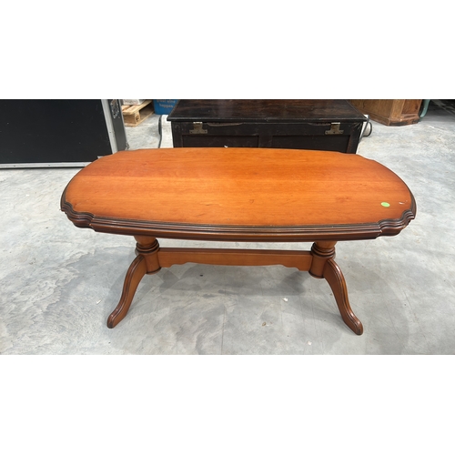 27 - Oval timber coffee table with serpentine-moulded edge top, twin turned column supports united by str... 