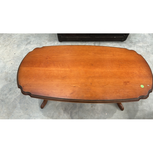 27 - Oval timber coffee table with serpentine-moulded edge top, twin turned column supports united by str... 