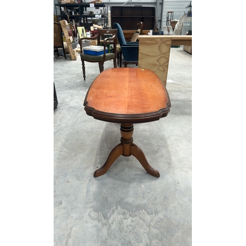 27 - Oval timber coffee table with serpentine-moulded edge top, twin turned column supports united by str... 