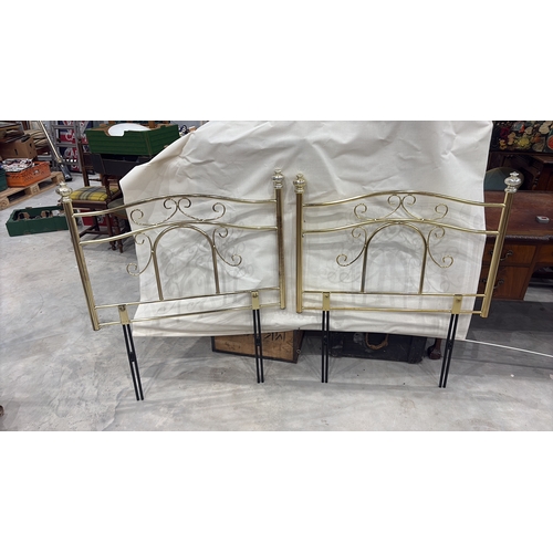 467 - Pair of tubular brass-finish single bed headboards, each with scrolled openwork panels and urn finia... 