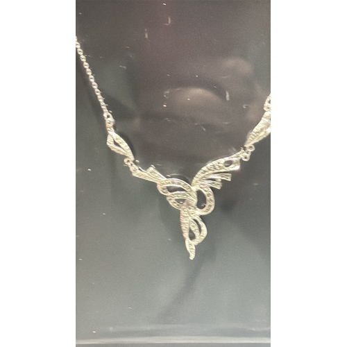 128 - Two silver tone marcasite jewellery items comprising a delicate chain necklace with scrolling ribbon... 