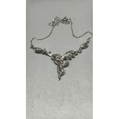 128 - Two silver tone marcasite jewellery items comprising a delicate chain necklace with scrolling ribbon... 