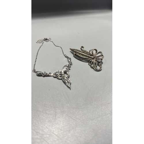 128 - Two silver tone marcasite jewellery items comprising a delicate chain necklace with scrolling ribbon... 