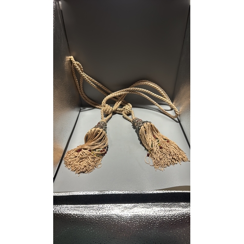 144 - Pair of cream twisted-cord curtain tiebacks, each terminating in an ornate metal mount set with colo... 